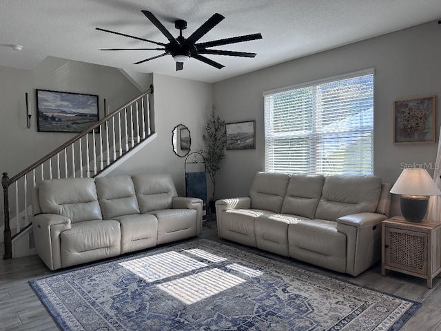 living room with hardwood / wood-style flooring, ceiling fan, and a textured ceiling