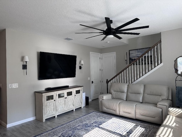 living room featuring dark wood-type flooring, ceiling fan, and a textured ceiling