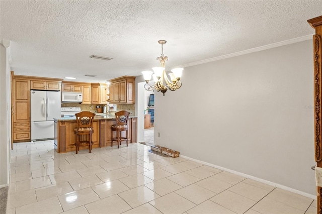 kitchen featuring pendant lighting, a kitchen breakfast bar, a chandelier, crown molding, and white appliances