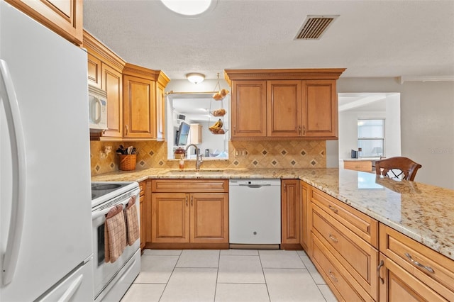 kitchen with light stone counters, white appliances, sink, and tasteful backsplash