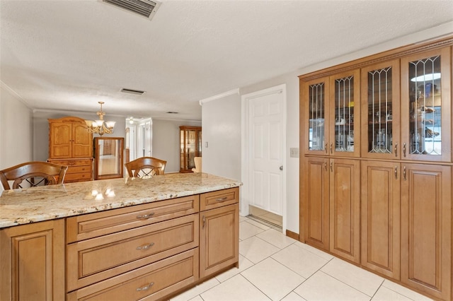 kitchen featuring light tile patterned flooring, a kitchen bar, an inviting chandelier, hanging light fixtures, and light stone countertops