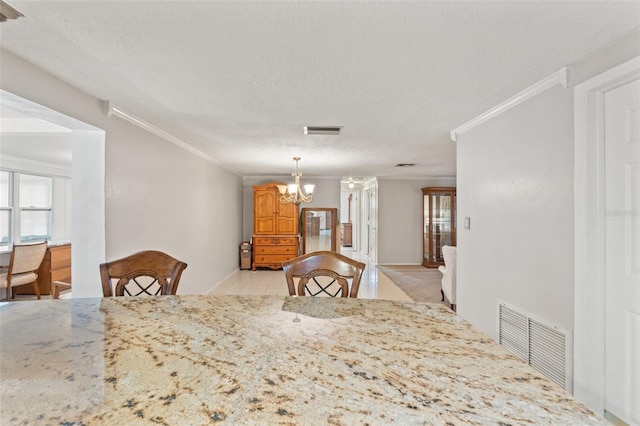 dining room with a textured ceiling, ornamental molding, a chandelier, and light tile patterned flooring