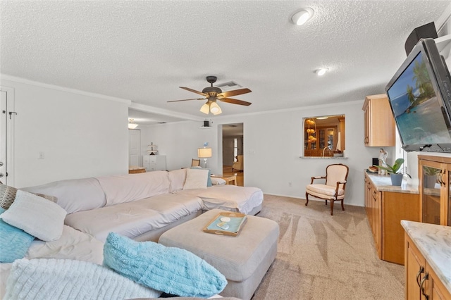 living room featuring ceiling fan, light colored carpet, ornamental molding, and a textured ceiling