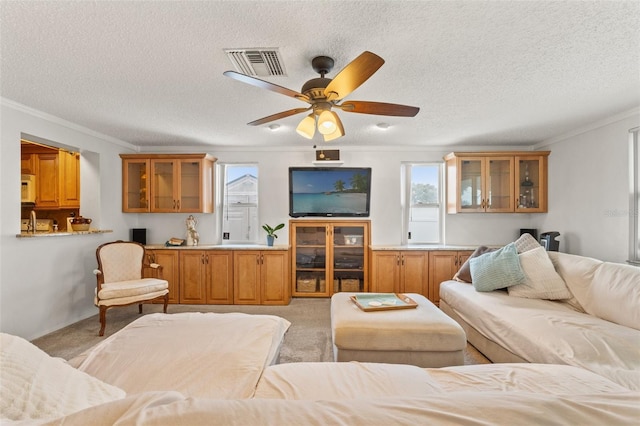 living room with crown molding, ceiling fan, light carpet, and a textured ceiling