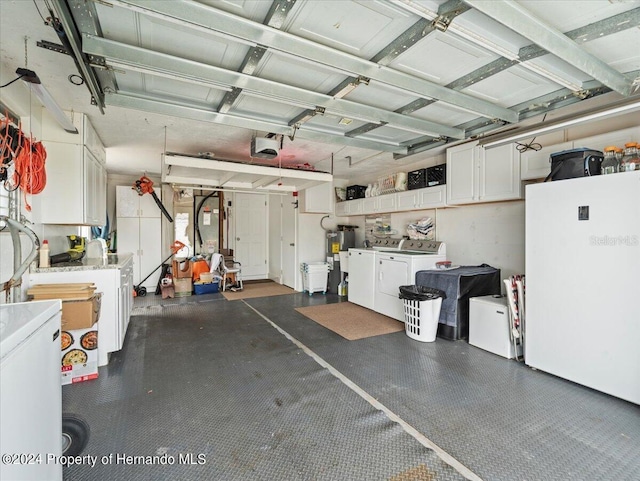 garage with a garage door opener, water heater, refrigerator, white refrigerator, and washer and dryer