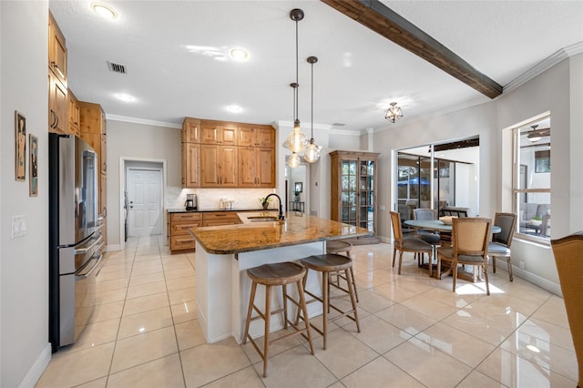 kitchen with stainless steel fridge, sink, dark stone countertops, light tile patterned flooring, and pendant lighting