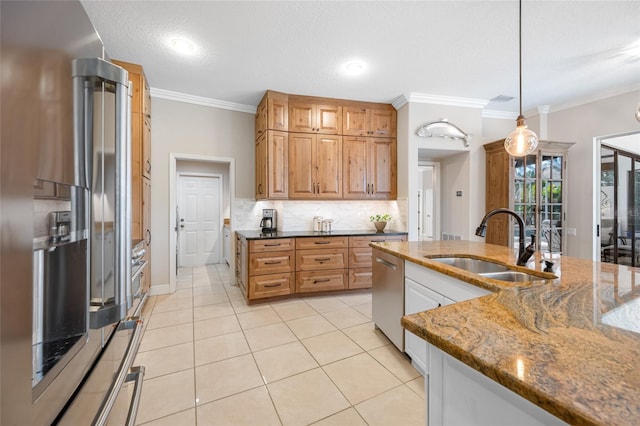 kitchen featuring dark stone countertops, sink, pendant lighting, stainless steel appliances, and crown molding