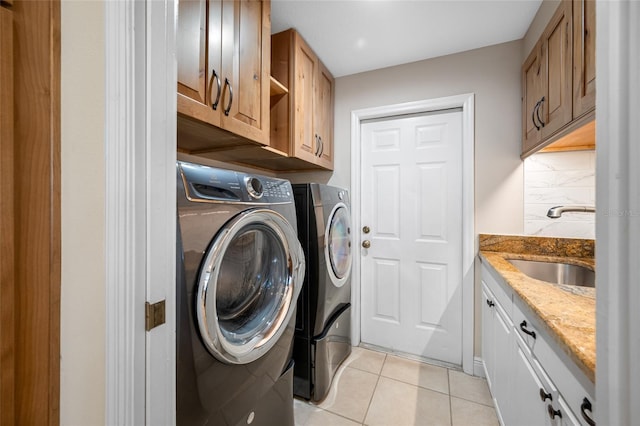 laundry room featuring light tile patterned floors, sink, cabinets, and independent washer and dryer