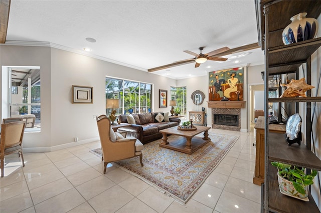 tiled living room with a tile fireplace, ceiling fan, a textured ceiling, and ornamental molding