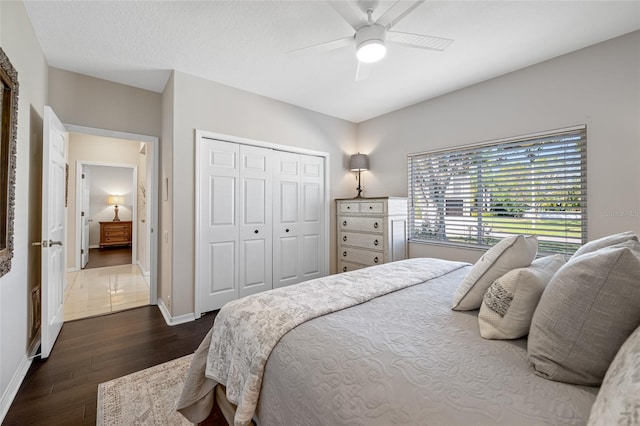 bedroom featuring ceiling fan, a closet, dark wood-type flooring, and a textured ceiling