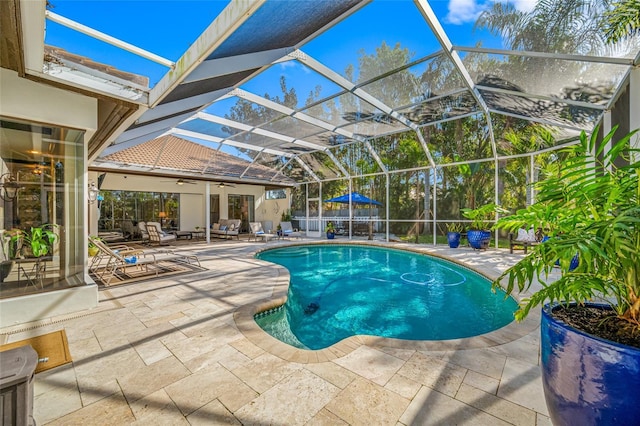 view of swimming pool with glass enclosure, ceiling fan, and a patio area