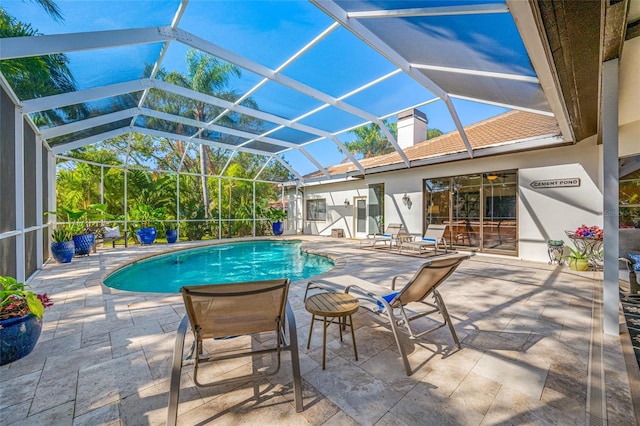 view of pool with glass enclosure and a patio area