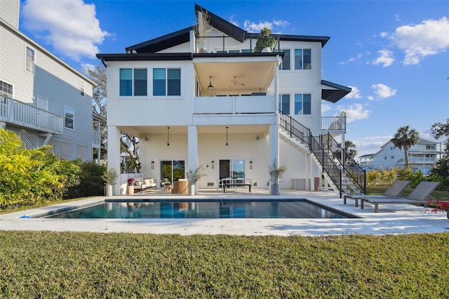 rear view of house with a balcony, a yard, and a patio area