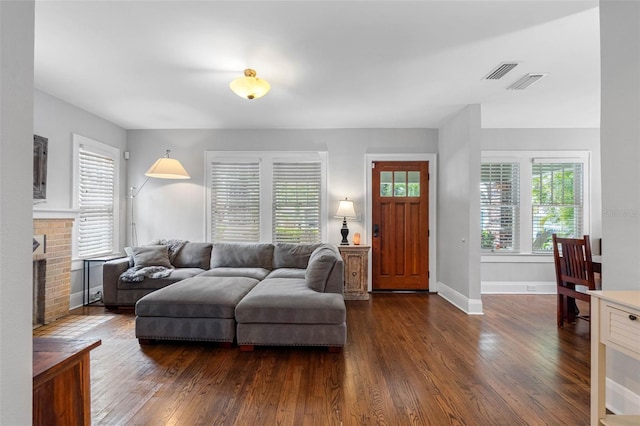 living room featuring a brick fireplace and dark hardwood / wood-style floors