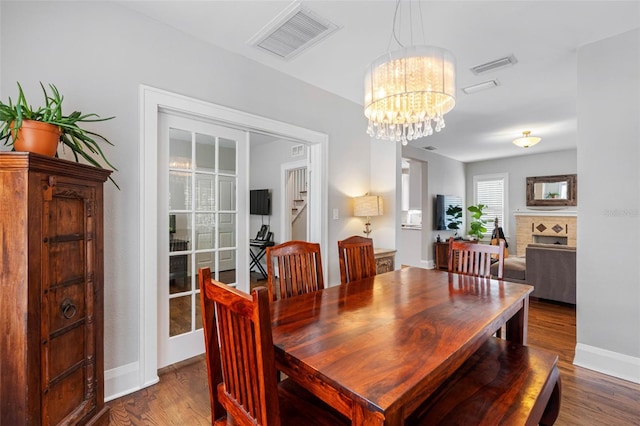 dining space with hardwood / wood-style floors and an inviting chandelier