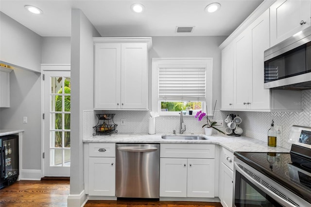 kitchen featuring white cabinetry, appliances with stainless steel finishes, sink, and light stone counters