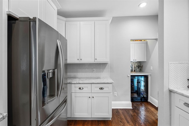 kitchen with stainless steel refrigerator with ice dispenser, white cabinetry, light stone counters, dark hardwood / wood-style floors, and backsplash