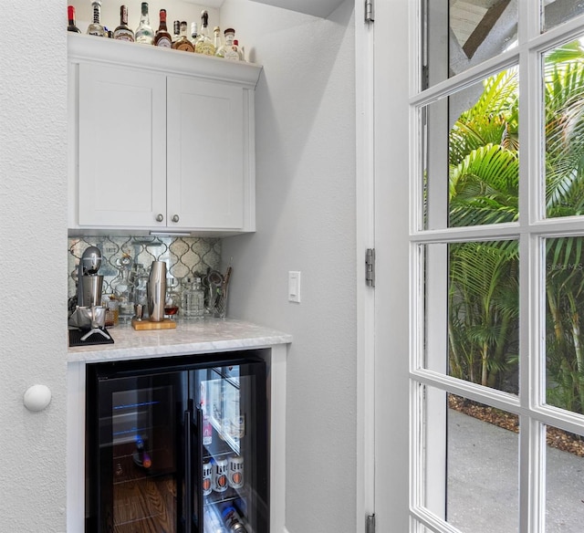 bar featuring tasteful backsplash, beverage cooler, and white cabinets