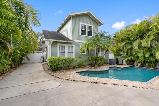 back of property featuring cooling unit and a fenced in pool