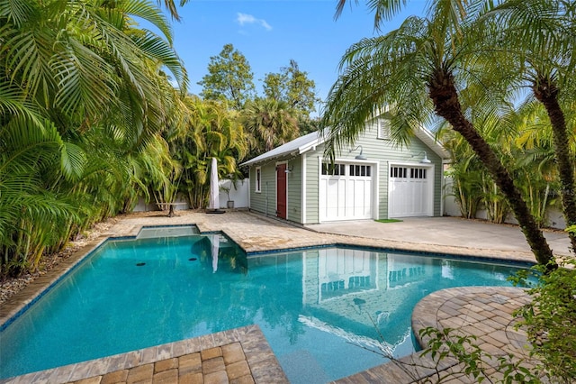 view of pool with a garage, a patio, and an outdoor structure