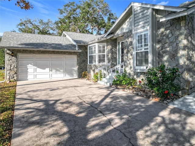 view of front of home with a garage, stone siding, roof with shingles, and concrete driveway