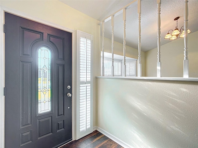 foyer featuring dark wood-style floors, an inviting chandelier, a wealth of natural light, and baseboards