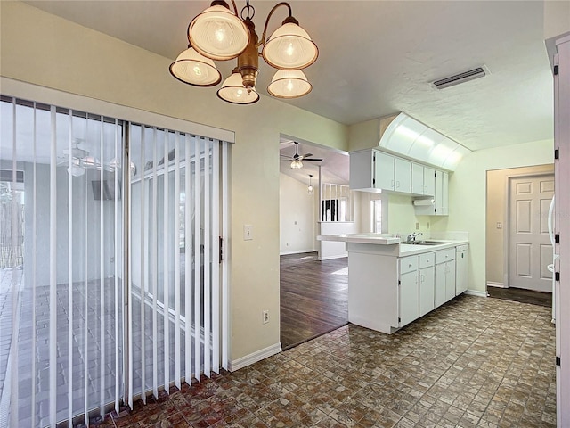 kitchen featuring light countertops, visible vents, white cabinetry, a peninsula, and baseboards