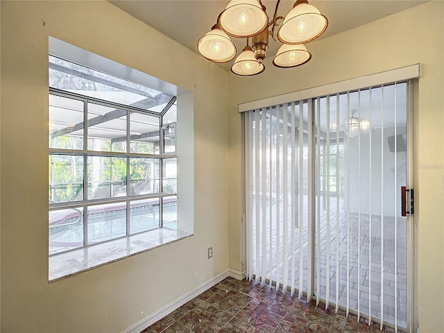 spare room featuring a chandelier and baseboards