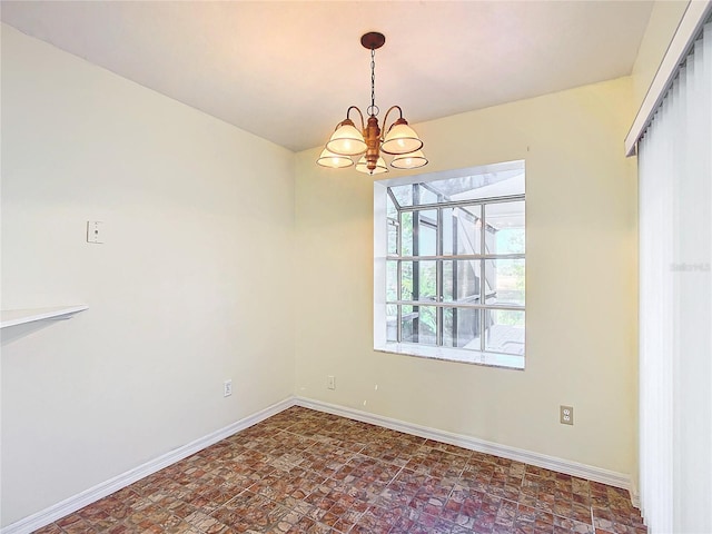 unfurnished room featuring baseboards and a notable chandelier