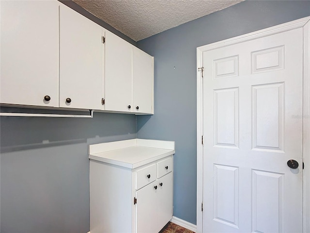 laundry area featuring a textured ceiling and baseboards