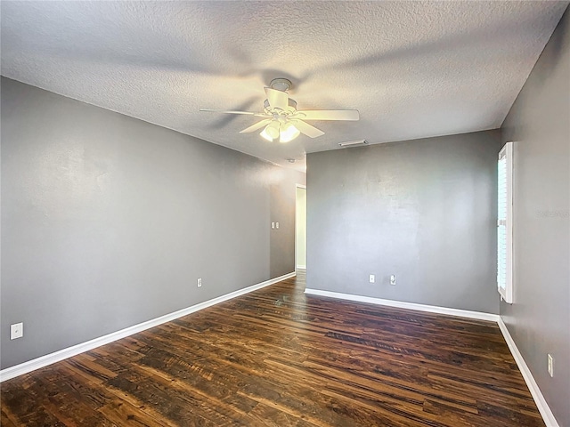 empty room featuring dark wood finished floors, visible vents, a ceiling fan, a textured ceiling, and baseboards