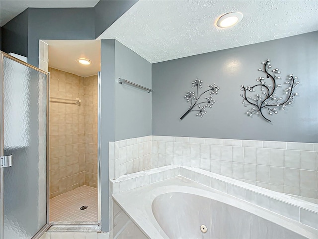 bathroom with a textured ceiling, a jetted tub, and a stall shower