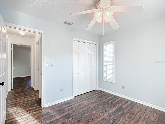 unfurnished bedroom featuring dark wood finished floors, a closet, visible vents, a textured ceiling, and baseboards