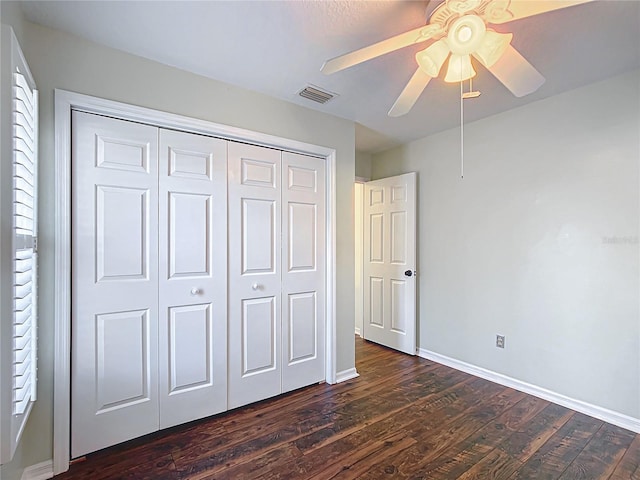 unfurnished bedroom featuring baseboards, visible vents, dark wood finished floors, and a closet