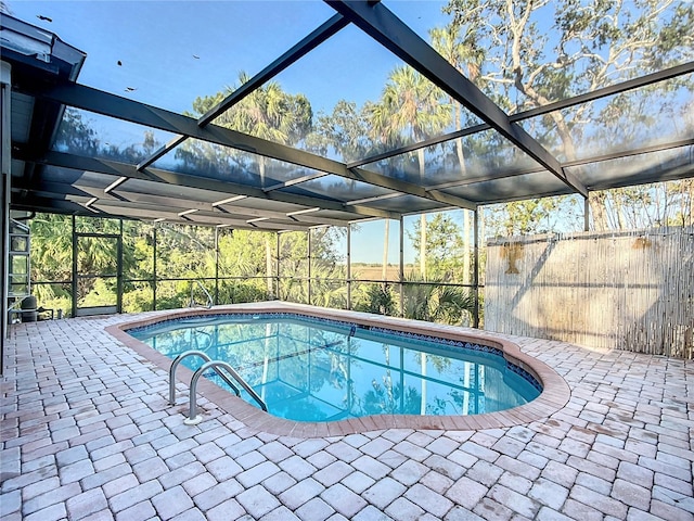 outdoor pool with glass enclosure, fence, and a patio