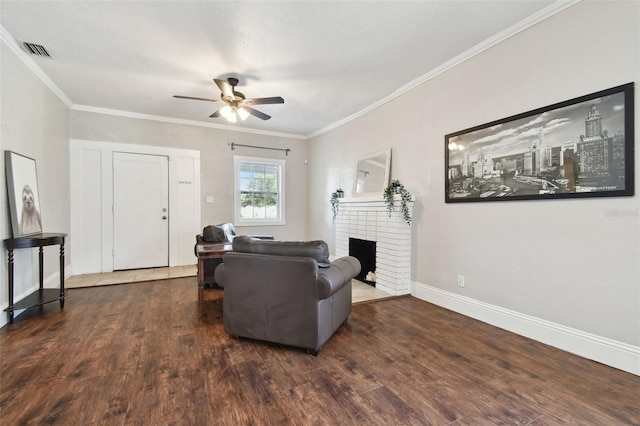 living room with crown molding, a brick fireplace, dark wood-type flooring, and ceiling fan