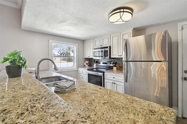 kitchen with white cabinetry, sink, decorative backsplash, stainless steel appliances, and light stone countertops