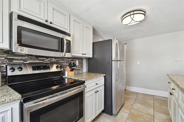 kitchen featuring tasteful backsplash, white cabinets, light stone counters, stainless steel appliances, and a textured ceiling