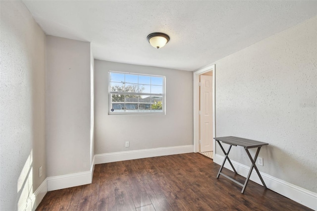 unfurnished room with dark hardwood / wood-style flooring and a textured ceiling