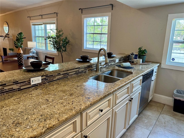 kitchen featuring plenty of natural light, sink, light stone countertops, and dishwasher