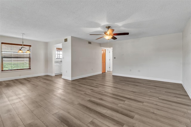 unfurnished room featuring a textured ceiling, ceiling fan, and light hardwood / wood-style flooring