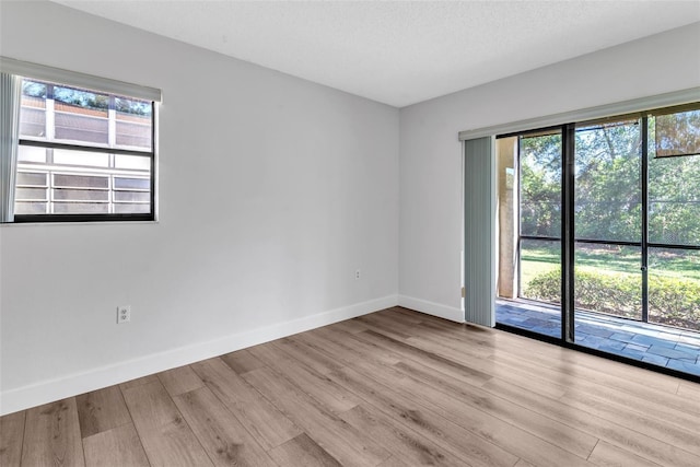 empty room featuring a textured ceiling and light hardwood / wood-style floors