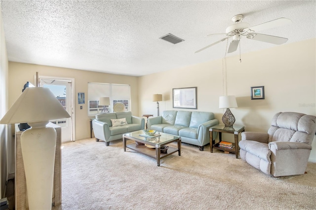 living room featuring ceiling fan, a textured ceiling, visible vents, and light colored carpet