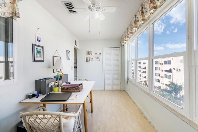 interior space featuring a ceiling fan, light wood-type flooring, visible vents, and baseboards