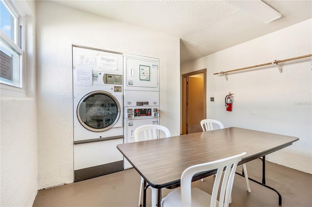 dining area with finished concrete floors, stacked washer / dryer, a textured wall, and a textured ceiling