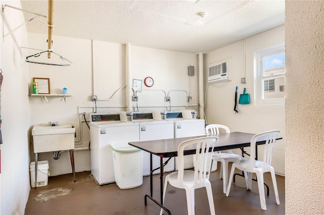 common laundry area featuring a textured ceiling, an AC wall unit, and washing machine and clothes dryer