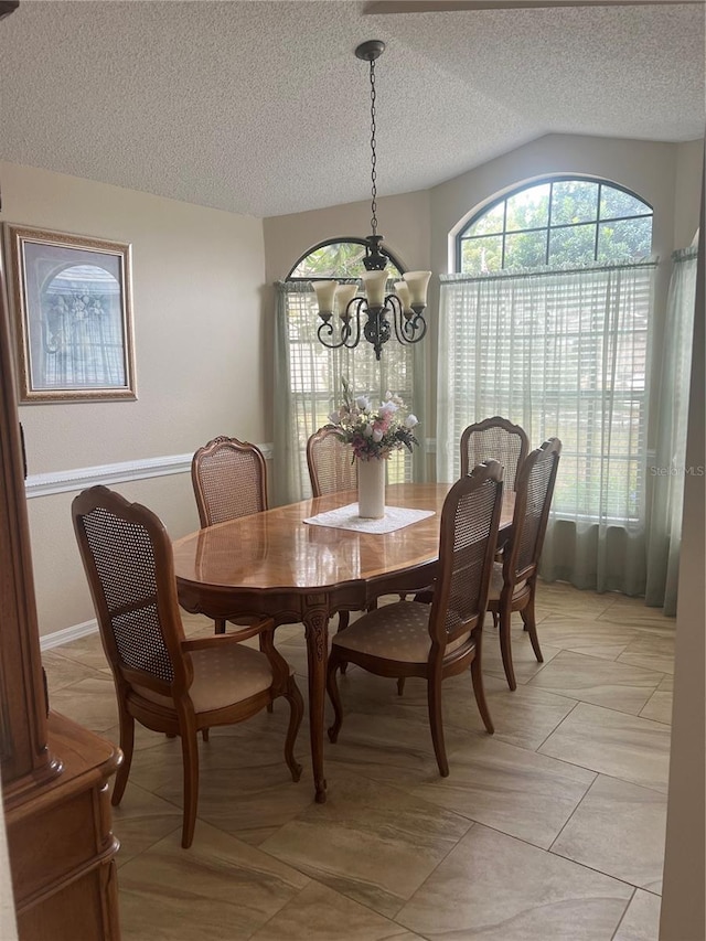 dining room featuring an inviting chandelier, vaulted ceiling, and a textured ceiling