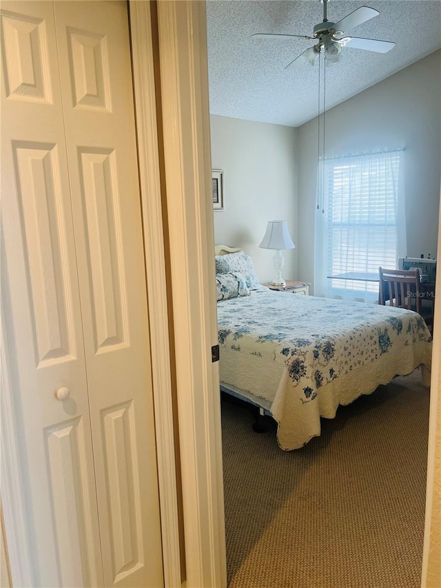 bedroom featuring vaulted ceiling, carpet flooring, ceiling fan, and a textured ceiling