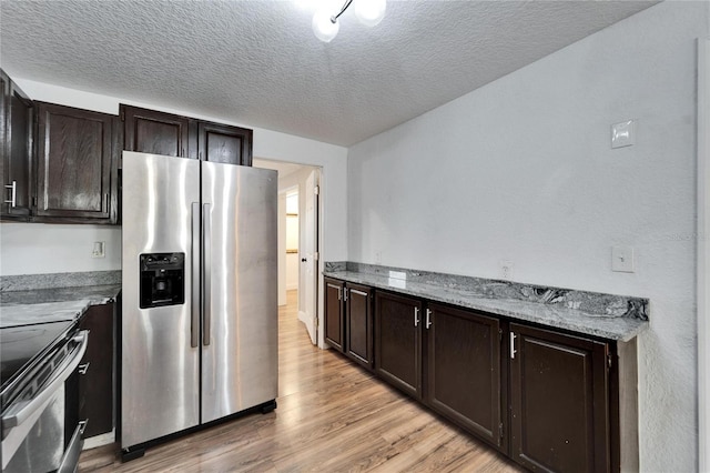 kitchen with stainless steel appliances, light stone countertops, light wood-type flooring, and dark brown cabinetry