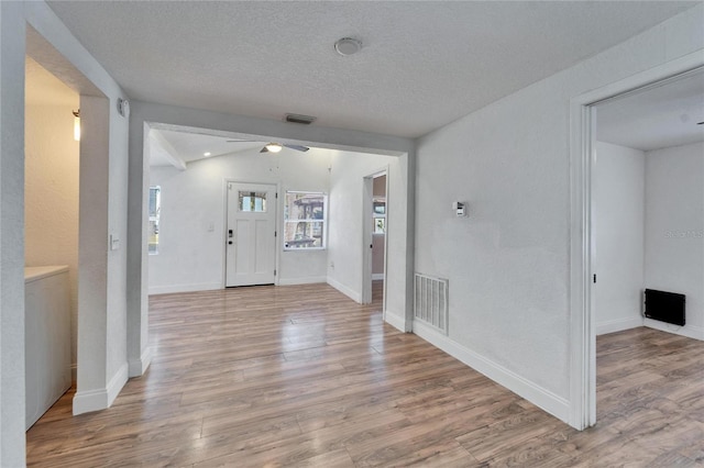 foyer entrance featuring lofted ceiling, a textured ceiling, and light wood-type flooring